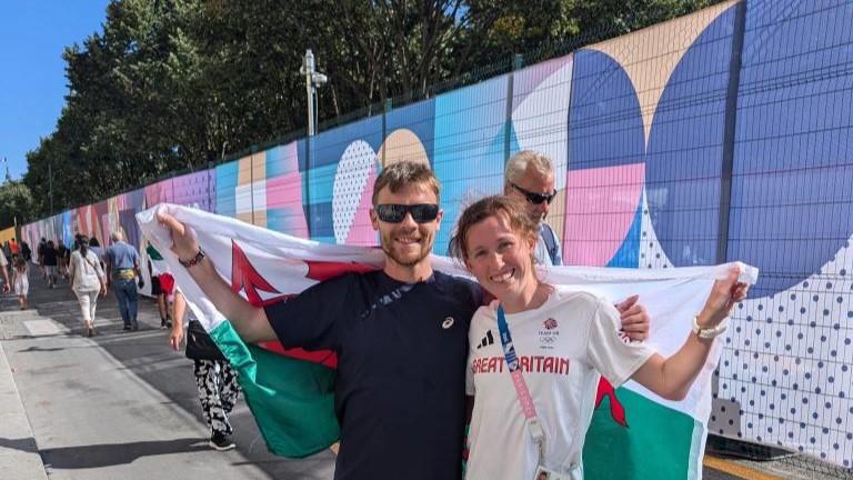 Clara Evans celebrating with Fiancé Paul holding the Welsh flag after the marathon 